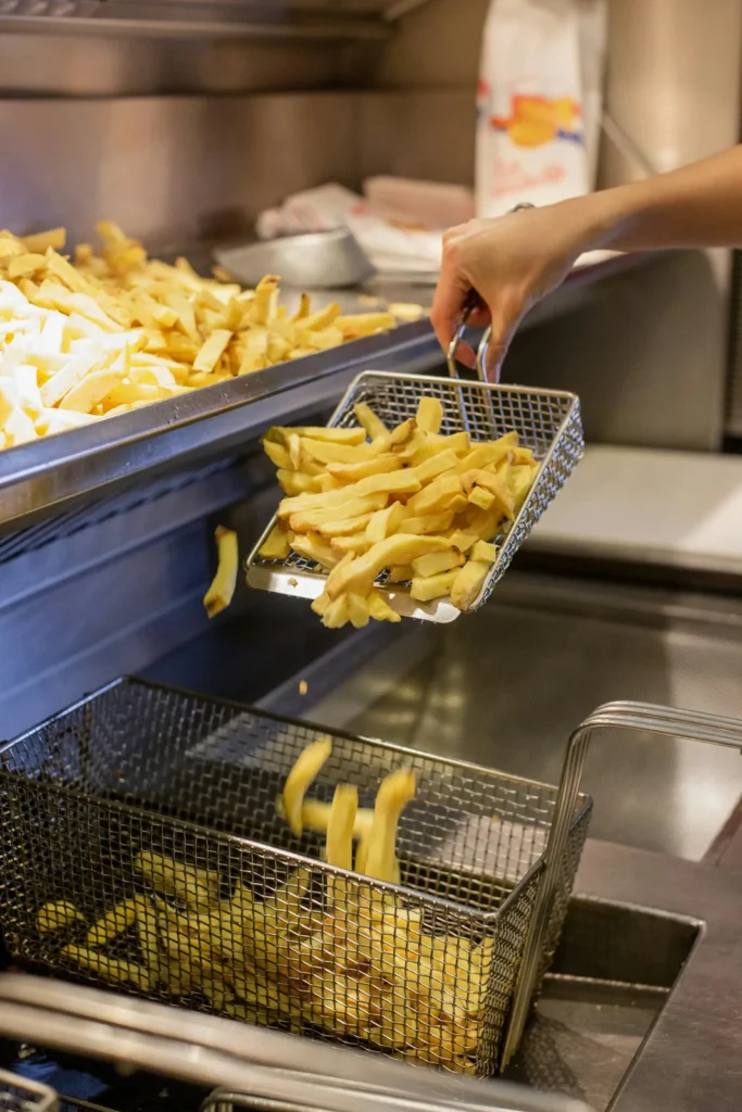 Frituurmand met goudgele friet vers uit de olie