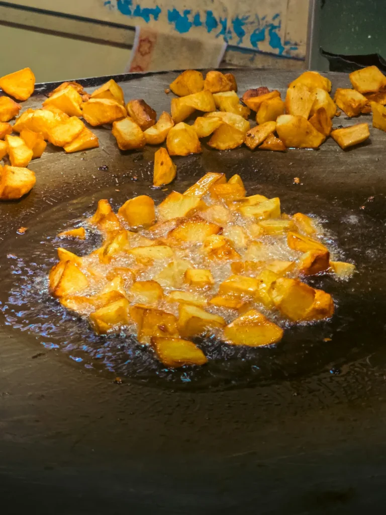 Goudbruine aardappelblokjes die bakken op een grote bakplaat